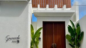 Una villa moderna con una porta in legno, pareti bianche e un balcone.