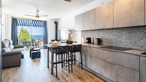 Uma cozinha moderna com vista para o mar, uma área de jantar com mesa e cadeiras, e um sofá.