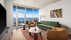 Uma sala de estar moderna com um sofá verde, duas poltronas, uma mesa de centro e um quadro na parede.