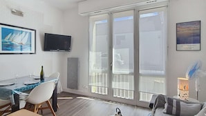Uma sala de estar moderna com área de jantar, televisão de tela plana, grande janela com vista e ventilador de teto.