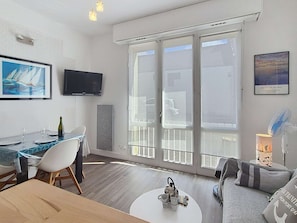 Un salon moderne comprenant un coin repas, un téléviseur à écran plat, une grande fenêtre offrant une belle vue et un ventilateur de plafond.