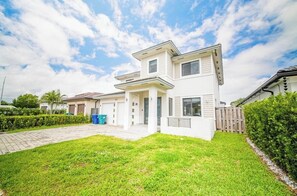 A two-story house with a paved driveway and a well-maintained lawn.