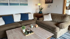 A living room with two sofas, a coffee table, wall art, and a lamp.