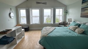 A bedroom with a bed, a ceiling fan, a window with a view, and a shelf with items.
