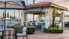 Uma área de bar ao ar livre, com piscina, espreguiçadeiras e um sinalizador de pedidos.