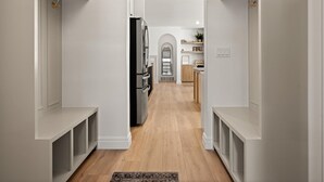 A hallway with white walls, a wooden floor, and a black refrigerator. - The Hyde Park Mountain Home (Hyde Park)