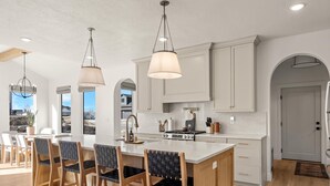 A modern kitchen with a central island, pendant lights, and wooden chairs. - The Hyde Park Mountain Home (Hyde Park)