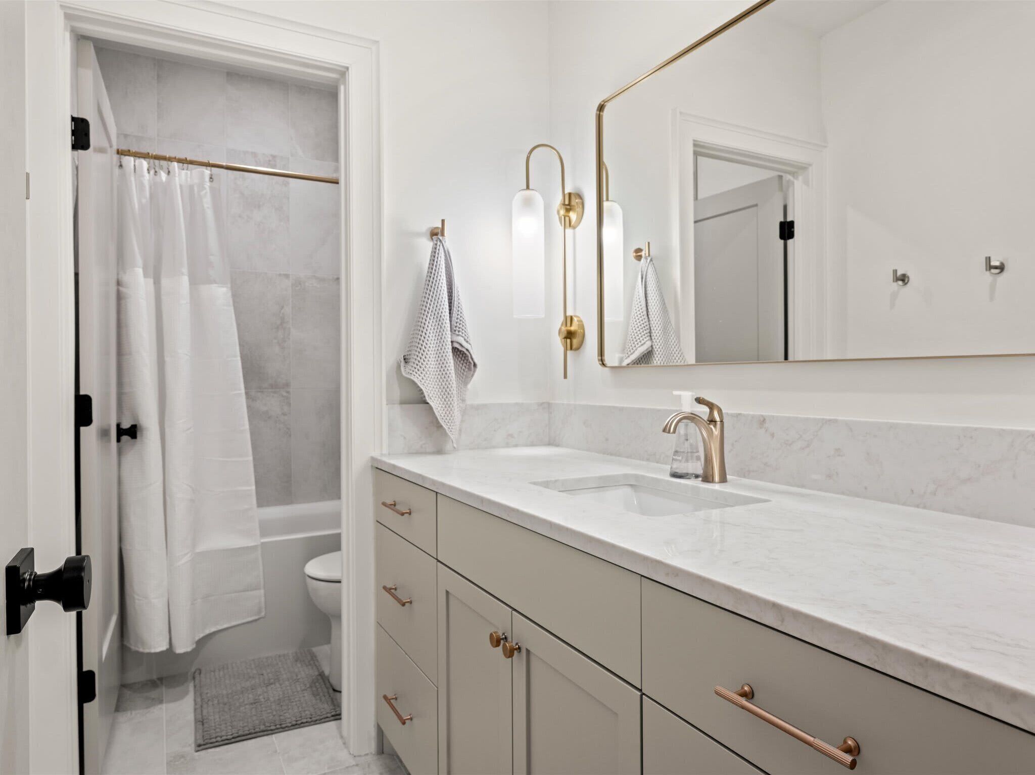 A modern bathroom with a shower, toilet, and vanity with a sink and mirror.