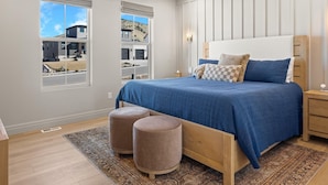 A bedroom with a large bed, two ottomans, a nightstand, and a window with a view of buildings. - The Hyde Park Mountain Home (Hyde Park)