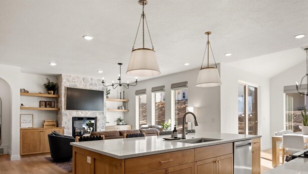 A modern kitchen with a central island, wooden cabinets, pendant lighting, and a stone accent wall. - The Hyde Park Mountain Home (Hyde Park)