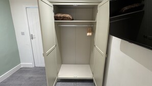 A walk-in closet with open doors, a white door in the background, and a flat-screen TV on the right. - Hammersmith Haven (London)