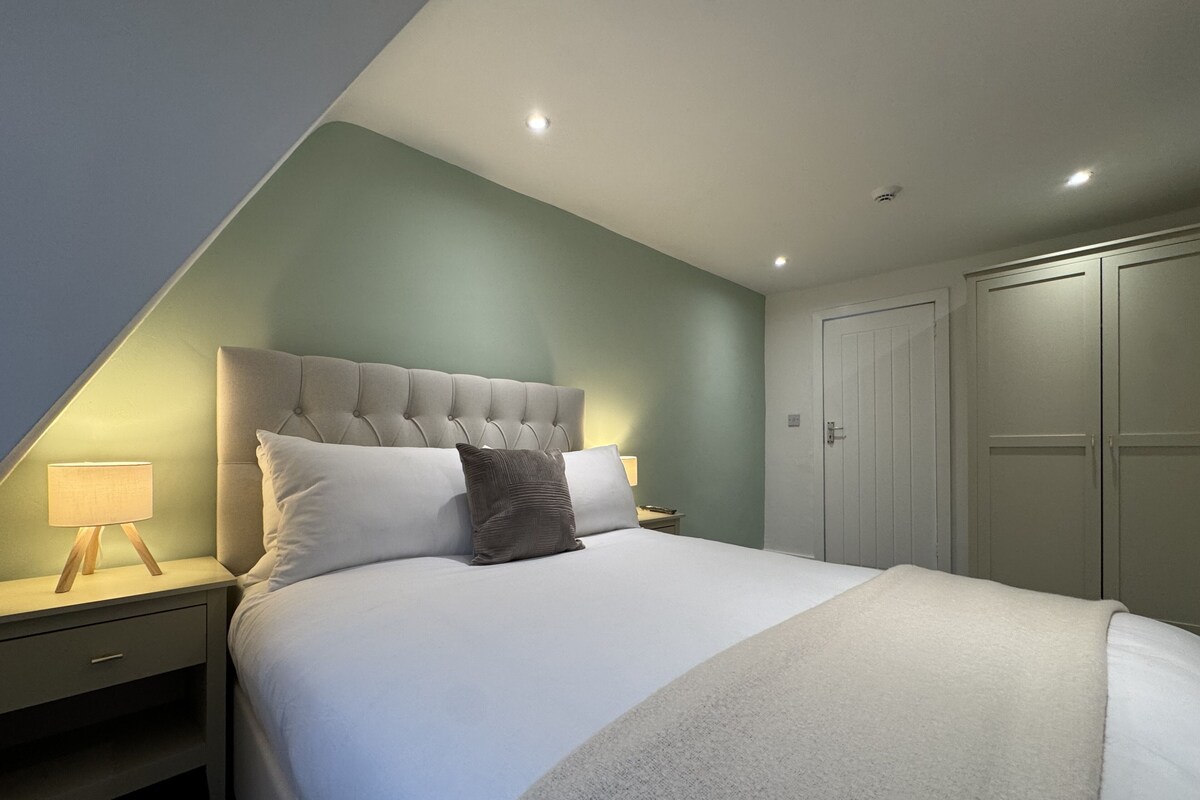 A bedroom with a bed, nightstands, a wardrobe, and a sloped ceiling.
