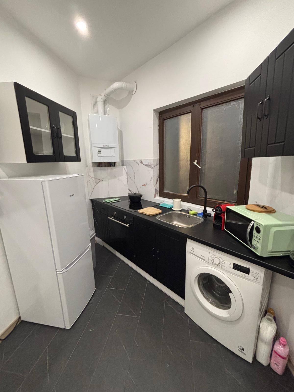 Une cuisine compacte équipée d’un réfrigérateur, d’un four à micro-ondes, d’un évier et d’un lave-linge.