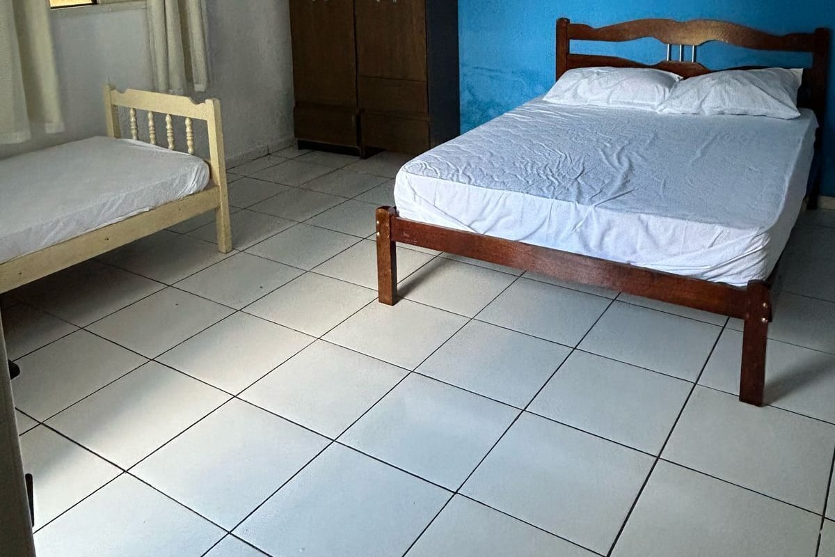 A bedroom with a single bed, a wardrobe, and an air conditioning unit.