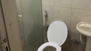 Ein Badezimmer mit Duschkabine, weißer Toilette und Waschbecken auf Säule.