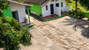 Ein kleines Haus mit Ziegeldach, einer Veranda und einem gepflasterten Einfahrt.