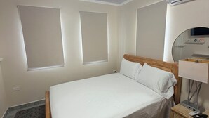 Une chambre à coucher comprenant un lit, une table de chevet, une lampe, un appareil de climatisation et un tapis à motifs.