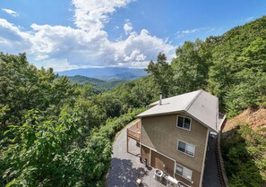 A two-story house with a sloped roof, a balcony, and a view of a forested valley. - Hummingbird Heights, Smoky Mt Views! Sleeps 10! (Bryson City)