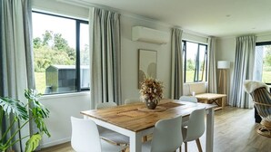 A dining area with a wooden table, white chairs, and a vase of flowers.
