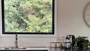 A modern kitchen with a large window, stainless steel appliances, and a potted plant.