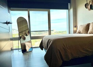 Ein Schlafzimmer mit einem Bett, einem großen Fenster und einem Spiegel.