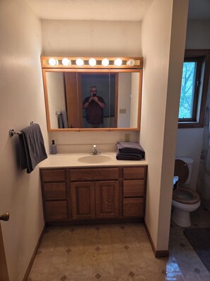 A bathroom with a vanity, mirror, and lights above the mirror.