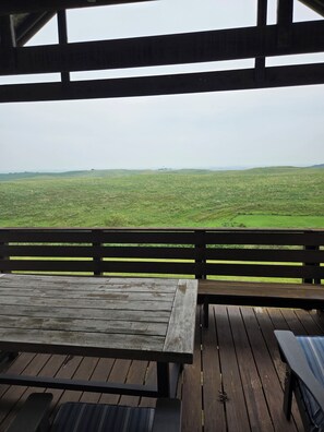 A wooden deck with benches overlooking a grassy field.