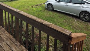 Un coche aparcado en un campo cubierto de hierba, con una terraza de madera al frente.