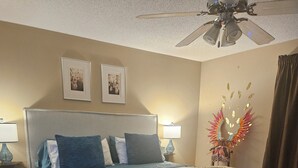 A bedroom with a bed, two wall-mounted lamps, a ceiling fan, and a decorative wall piece. - Spacious 4-bedroom house in tranquil Jonesboro with AC (Jonesboro)