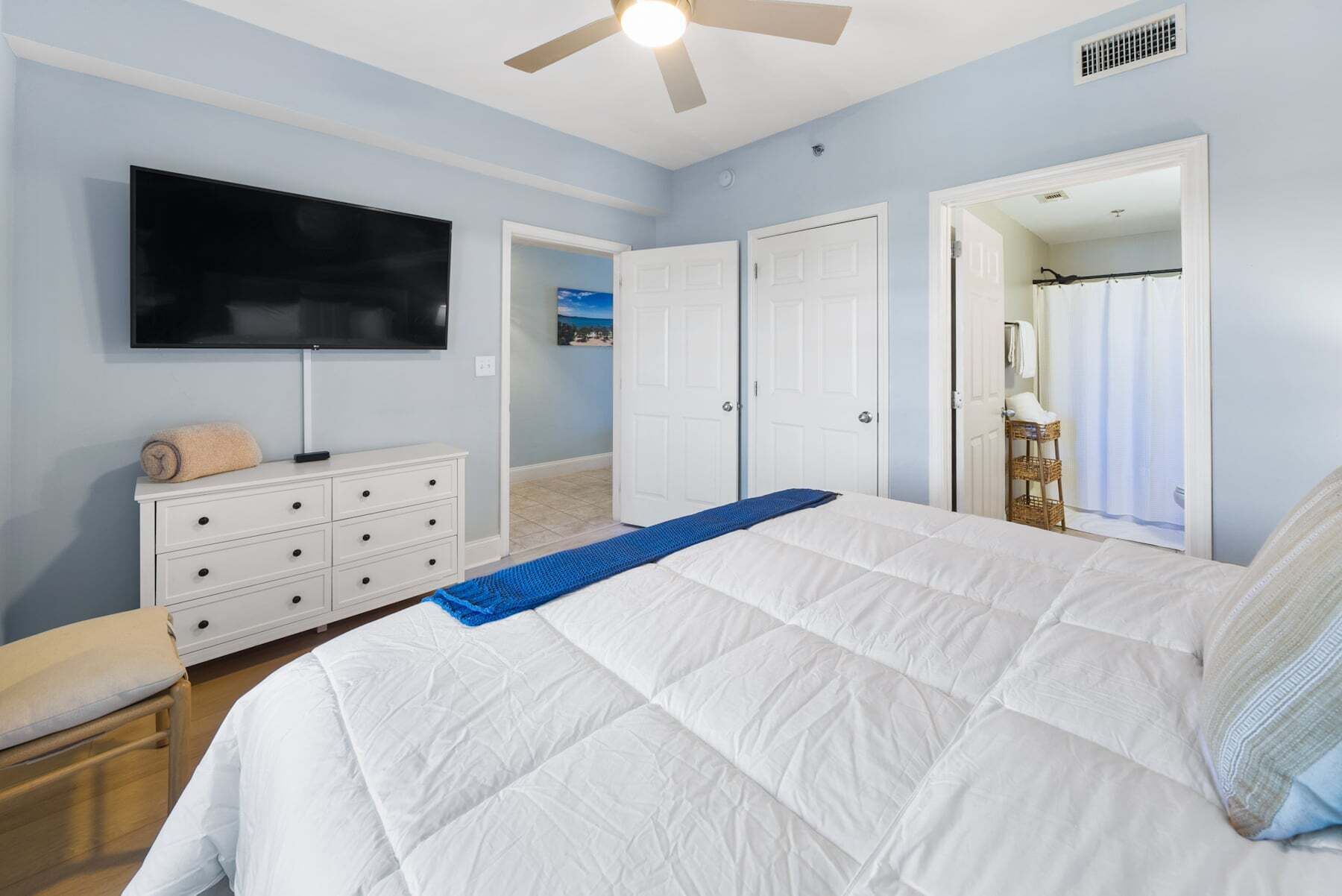Une chambre à coucher comprenant un lit, une télévision, une commode et une porte donnant sur une salle de bain.