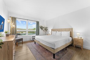 A bedroom with a large bed, bedside tables, a desk, and a view of the outdoors. - Relaxing Lake Taneycomo Condo Steps from Downtown Branson (Branson)