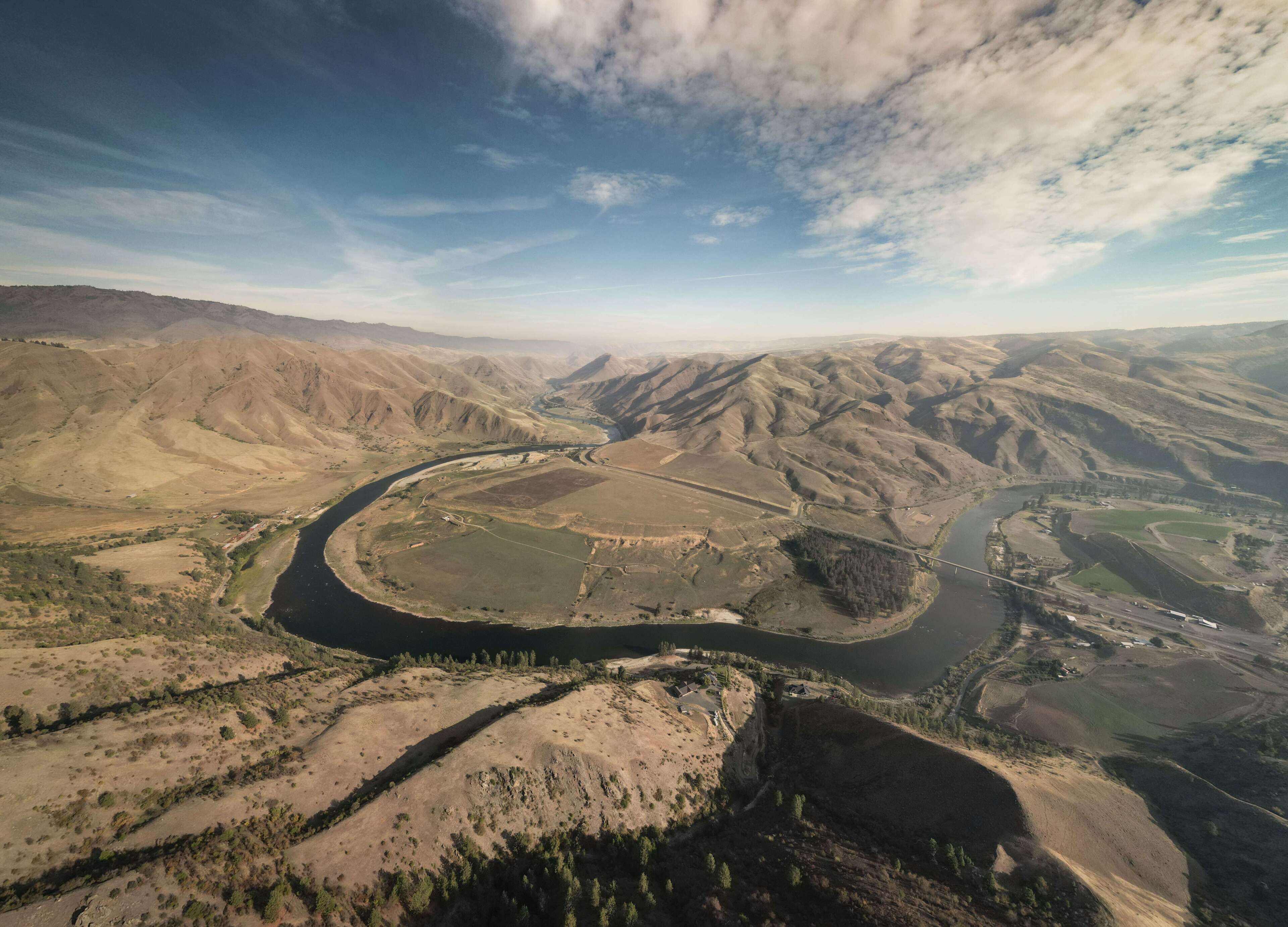 Une rivière qui serpente à travers une vallée, entourée de collines.