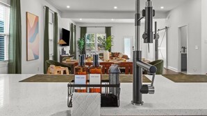 A modern kitchen with a central island, a built-in oven, and a large range hood. - Delightful 4 Bedroom Home with Hot Tub, Game Rm, Putt Putt,Near Mercedez Stadium (Atlanta)