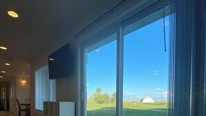 A spacious room with a large sliding glass door leading to a balcony, a flat-screen TV mounted on the wall, and a tiled floor. - Hunter's dream with 640 acres of hunting land (Brocket)
