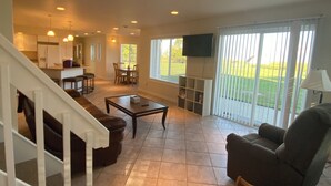 A spacious living area with a staircase, a dining table, and a television. - Hunter's dream with 640 acres of hunting land (Brocket)