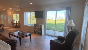 A spacious living room with a large window, a flat-screen TV, and a dining area. - Hunter's dream with 640 acres of hunting land (Brocket)