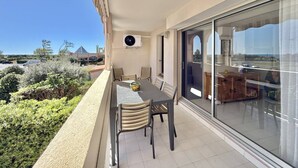 A balcony with a table and chairs, a large window, and a view of the surrounding landscape. - CAP D'AGDE - Plage Richelieu / Réf 307 (CAP D'AGDE)