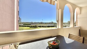 A dining area with a table, chairs, a basket of fruit, and a view of a green landscape through a window. - CAP D'AGDE - Plage Richelieu / Réf 307 (CAP D'AGDE)