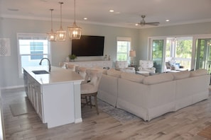 A spacious living area with a large sofa, a kitchen island, and a flat-screen TV. - New Listing! 4 Bedroom Villa Lost Key| Free Activities |Golf |Two pools |Private Beach Club (Pensacola)