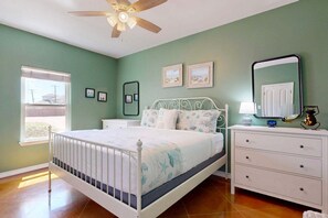 A bedroom with a bed, a nightstand, a dresser, a ceiling fan, and a window. - PB117 Shared Pool, Pet Friendly, Parking for 3, Charcoal Grill (Port Aransas)