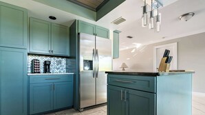 Una cucina con mobili color acquamarina, un frigorifero in acciaio inossidabile e un piano di lavoro con un portacoltelli.