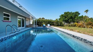 Una piscina con acqua cristallina, una casa con balcone e un prato curato.