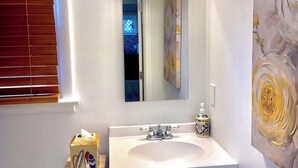 Ein Badezimmer mit einem weißen Waschbecken, einem Spiegel und einer Leuchte darüber.