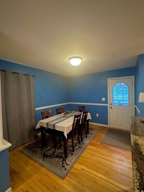 A dining area with a table set for four, a door with a window, and a ceiling light. - Rockville Private Oasis (Rockville)