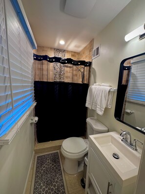A compact bathroom with a toilet, sink, and shower area.