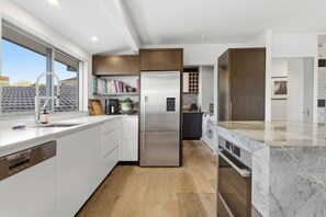 Una cocina moderna con armarios blancos, un refrigerador de acero inoxidable y una encimera de mármol.