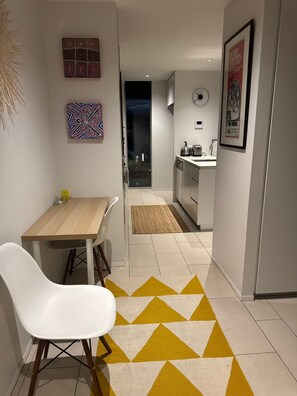 Un interior moderno con comedor, cocina y un pasillo que lleva a un balcón.