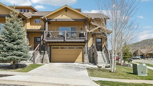 A two-story house with a front porch, a garage, and a small staircase leading to the second floor. - Family Mountain Retreat | Private Hot Tub (Hideout)