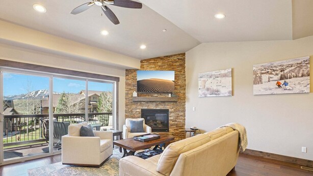 A spacious living room with a fireplace, large windows, and a balcony. - Family Mountain Retreat | Private Hot Tub (Hideout)