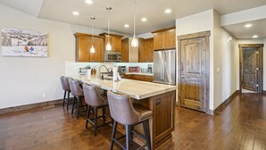 A modern kitchen with wooden cabinets, stainless steel appliances, and pendant lighting. - Family Mountain Retreat | Private Hot Tub (Hideout)